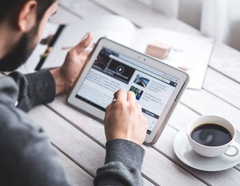 Man using a tablet while browsing the internet for examples on online portfolio