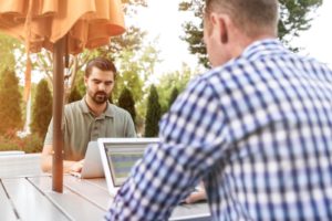 two men working as recruiters on LinkedIn looking at their laptops as they check through potential candidates for hiring