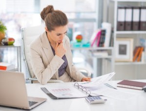 Thoughtful business woman documents in office looking at her resignation letter