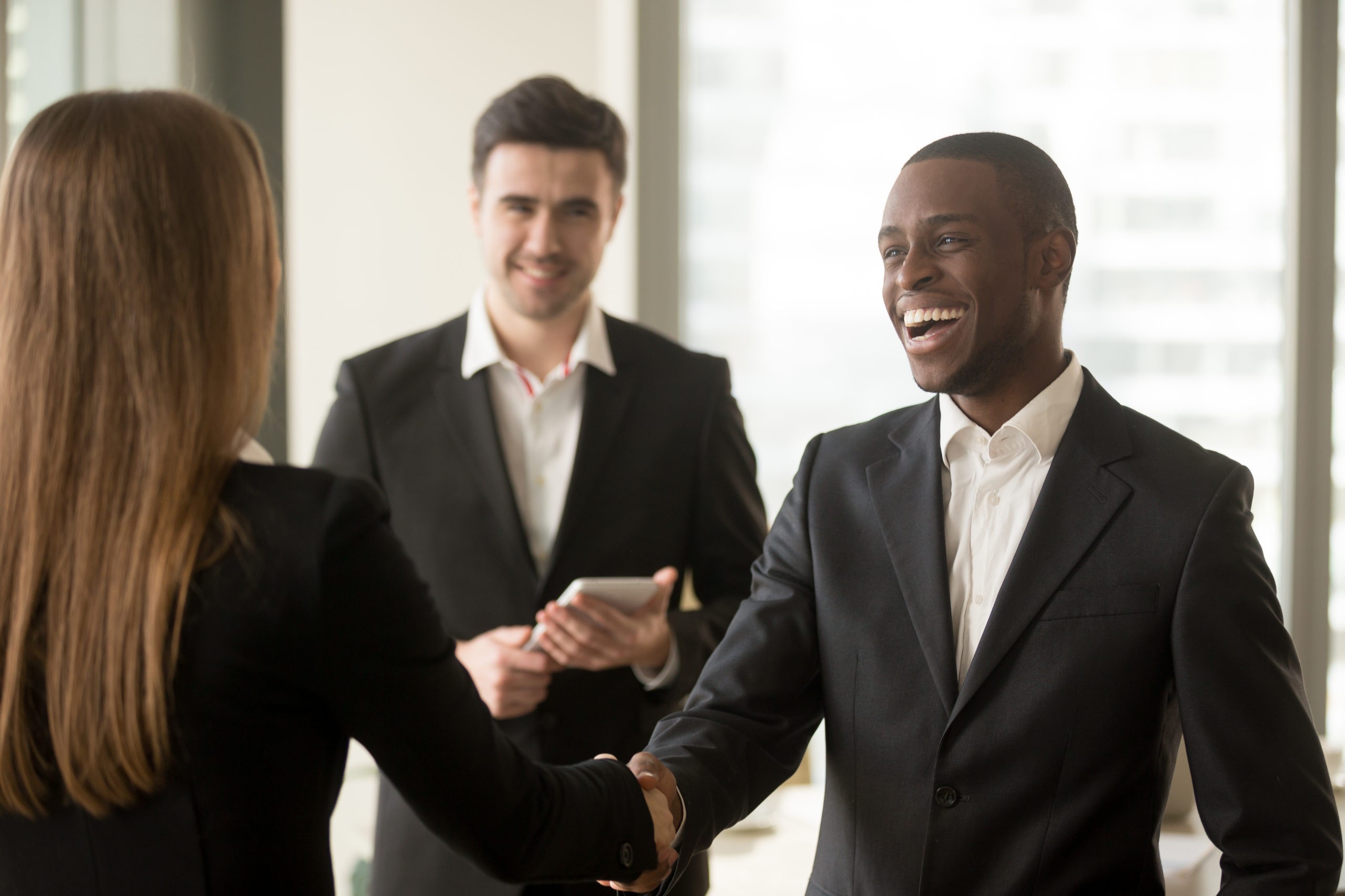 Smiling guy shaking hands with a woman in suits in his new job making a good impression