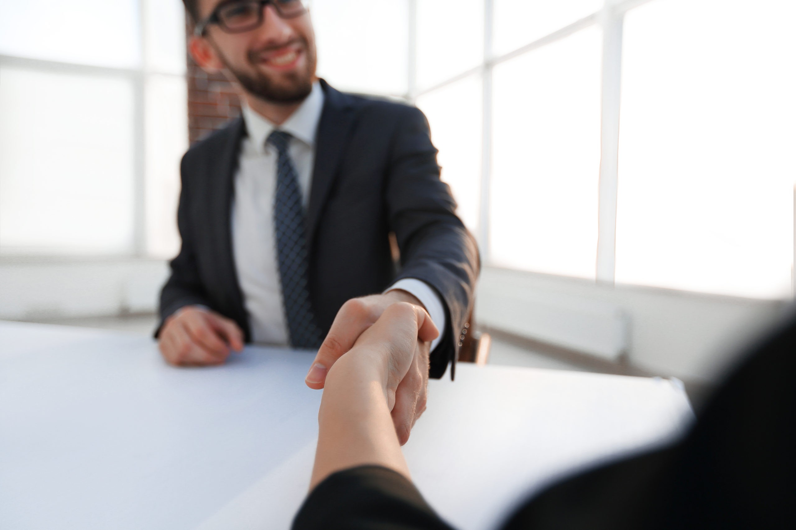 a visually impaired hiring manager shaking hands with a top applicant after an interview